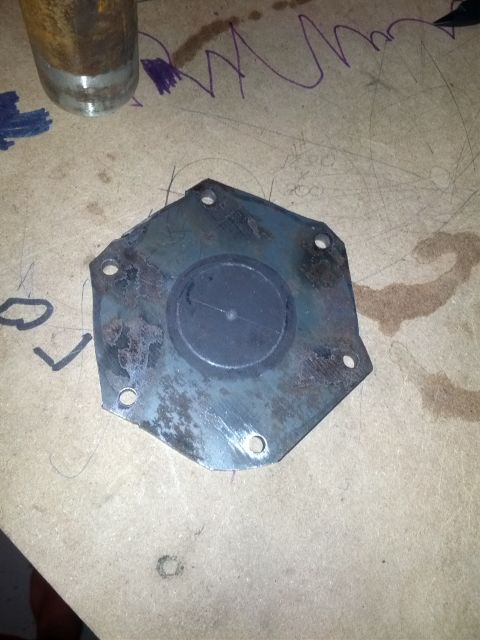 1989 BMW 3 Series - A close-up view of a metal plate with a rubber seal, resting on a surface with some markings.