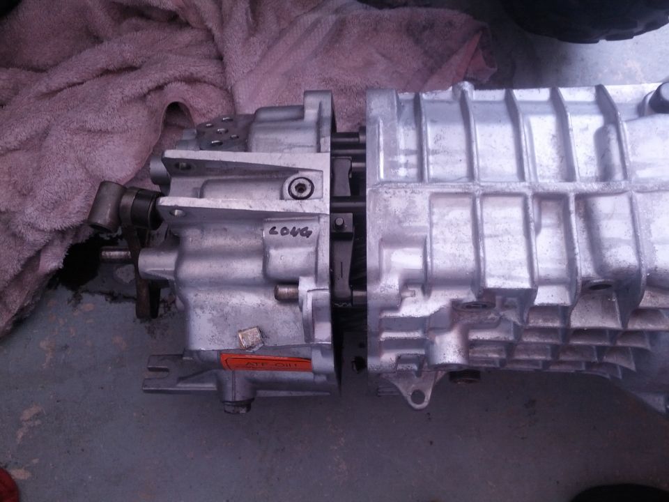 Two aluminum transmission housings are joined together. One has 'LONG' written on it