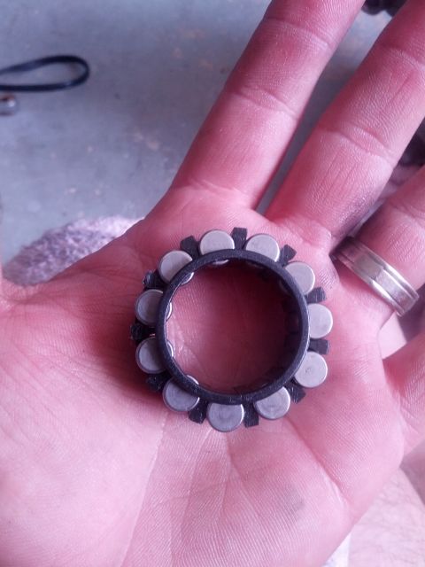 1989 BMW 3 Series - A bearing part is held in a hand, showing its roller bearings and black casing.