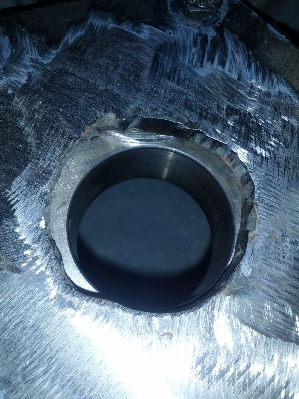 Close-up of a rough metal component with a circular opening and tool marks