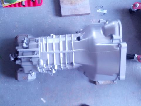 1989 BMW 3 Series - A silver transmission is shown from the side, resting on a concrete surface.