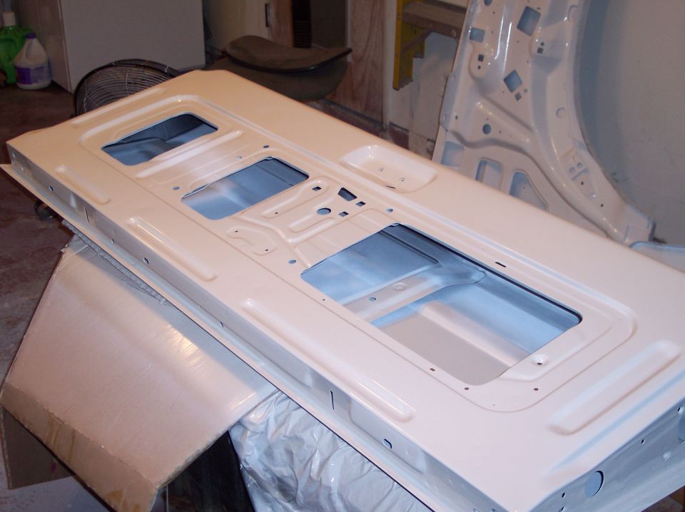 Unpainted car door panel with multiple cutouts, resting on a box