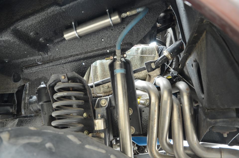 Undercarriage of a vehicle showing suspension springs, shocks, and exhaust headers