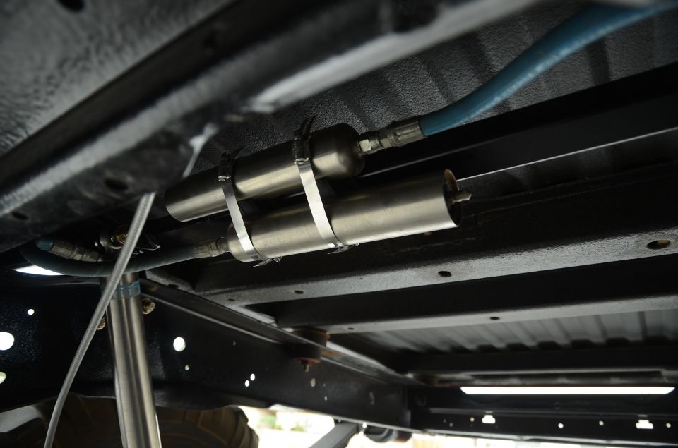 Underbody of vehicle showing dual canisters and blue hose, with Supermotors.net logo