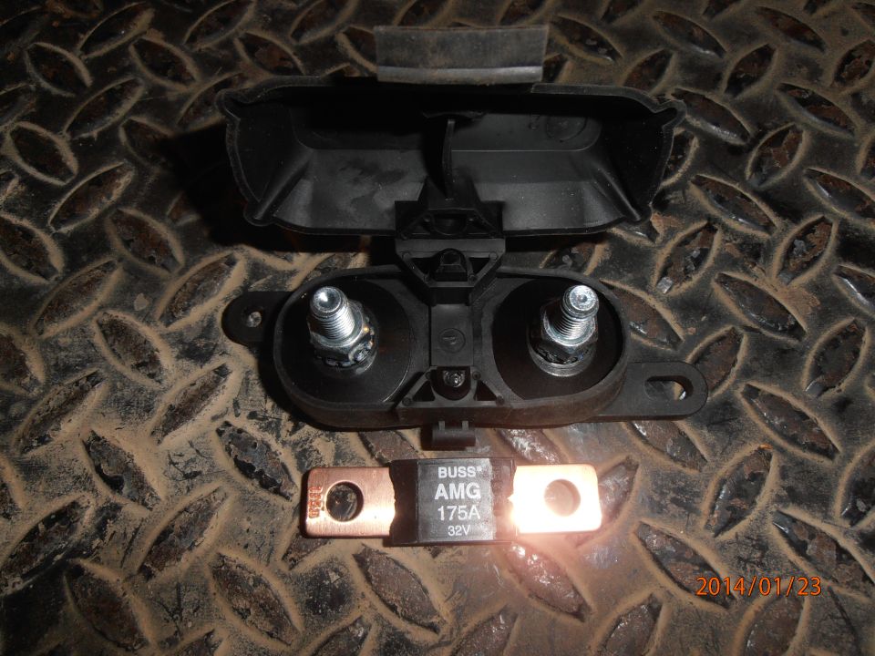 Black plastic fuse holder with two bolts and a separate 175A AMG fuse on a metal surface