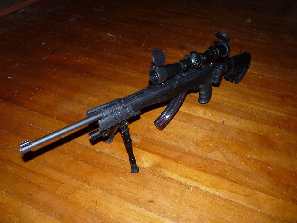 Rifle with scope and bipod on a wooden floor