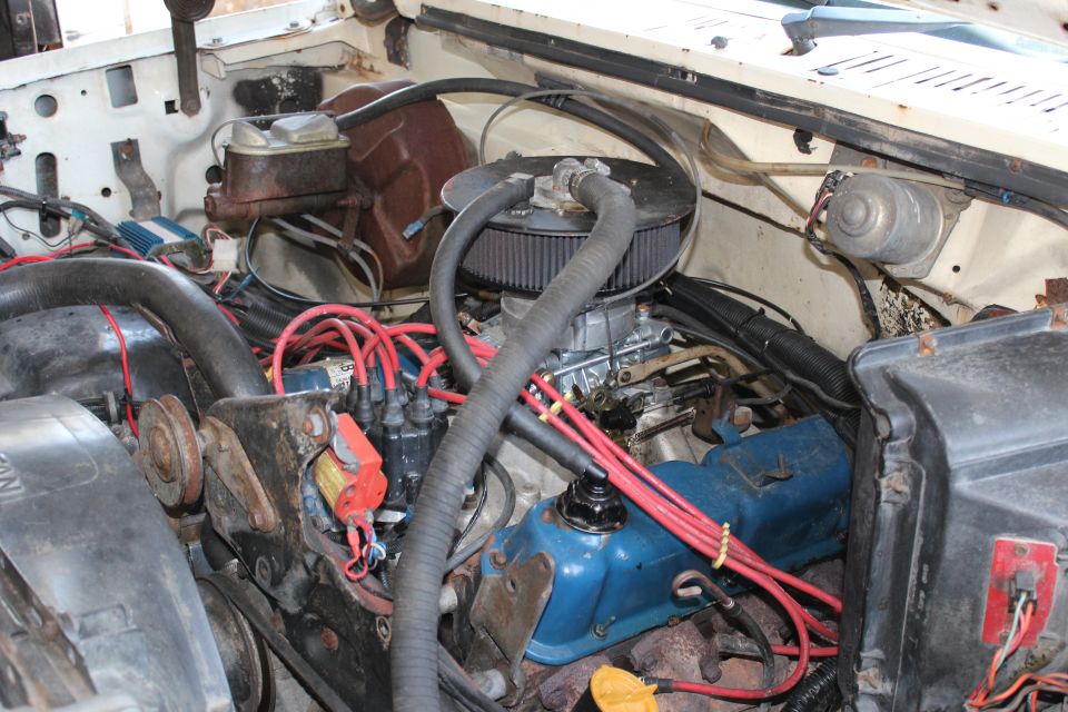 Engine bay with carburetor, distributor, and red spark plug wires