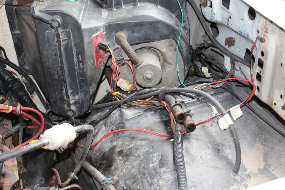 Firewall of a truck engine bay showing HVAC blower motor housing and exposed wiring harnesses and hoses