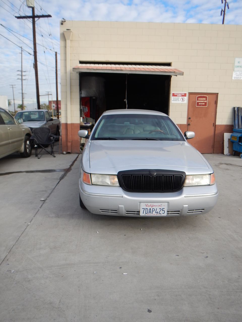 Front view of a silver four-door sedan parked outside an auto shop