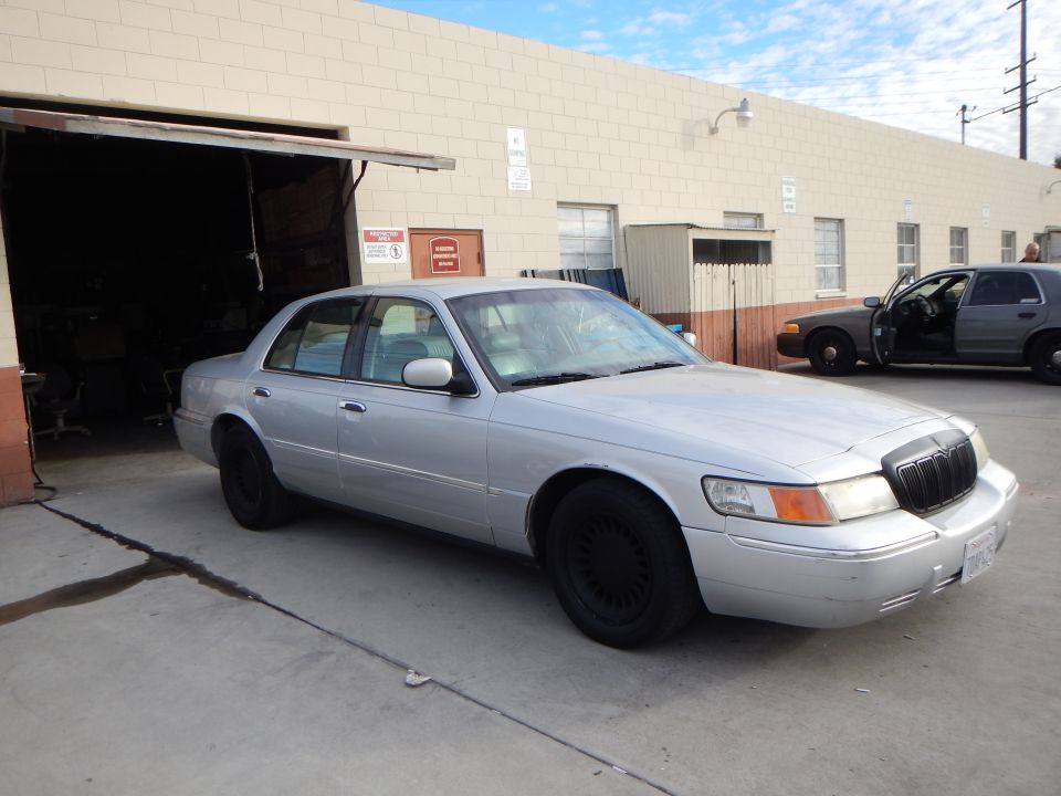 Silver four-door sedan with black wheels parked at an auto shop