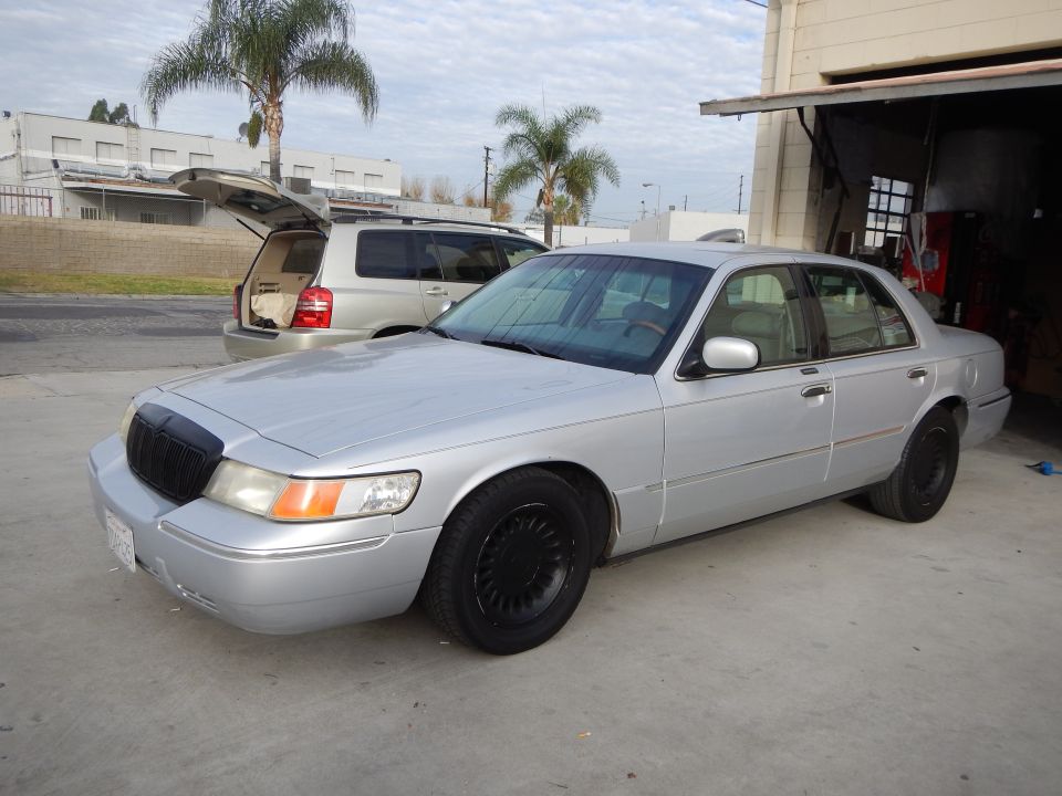 Silver Mercury sedan with black grille and wheels at an auto shop