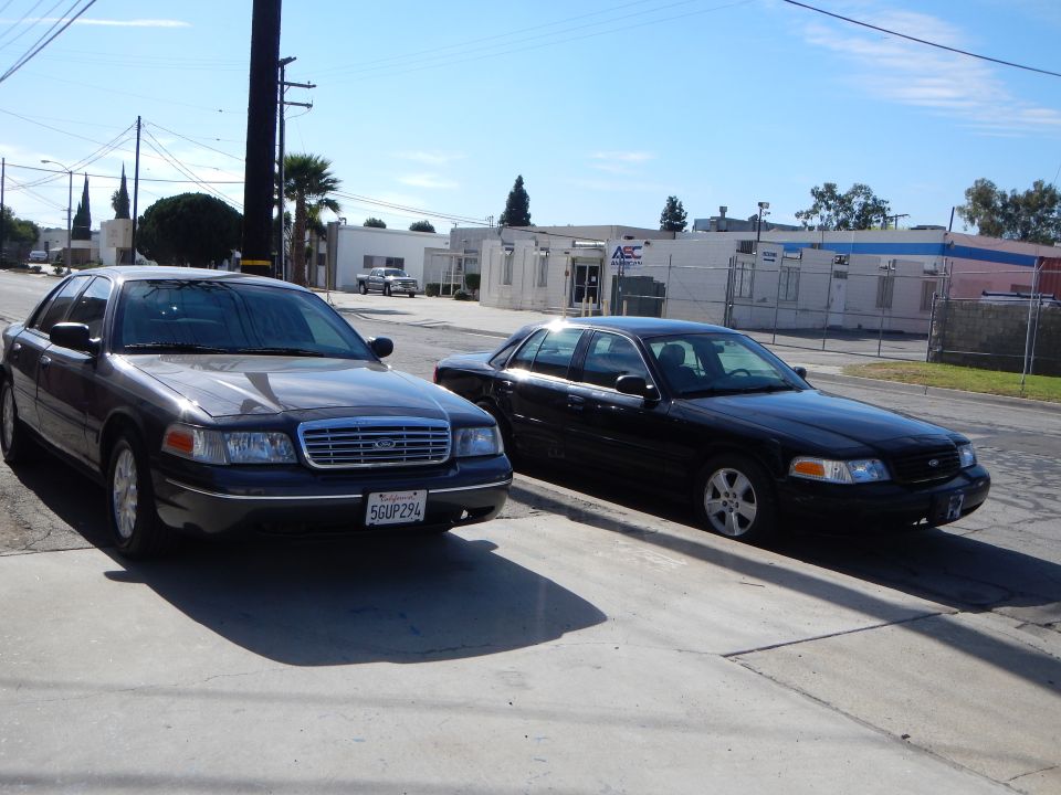 gray and a black Ford Crown Victoria parked side by side on an industrial street, plate 5GUP294