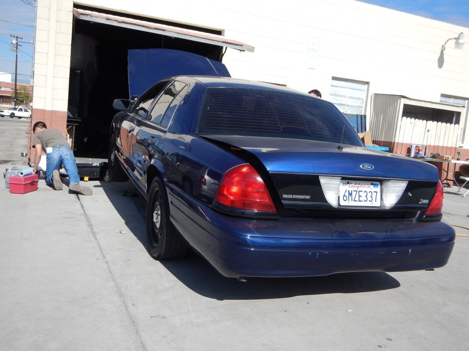 Rear of dark blue Ford Crown Victoria with open hood, plate 6MZE337