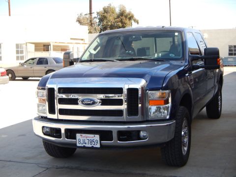 2003 Ford Crown Victoria - Front three-quarter view of a dark blue Ford Super Duty crew-cab pickup parked in a paved lot, California plate 8JC7859.