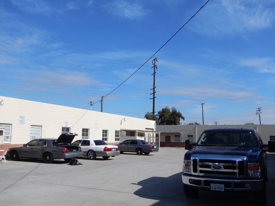 Silver sedans and dark blue Ford pickup parked in a wide paved lot