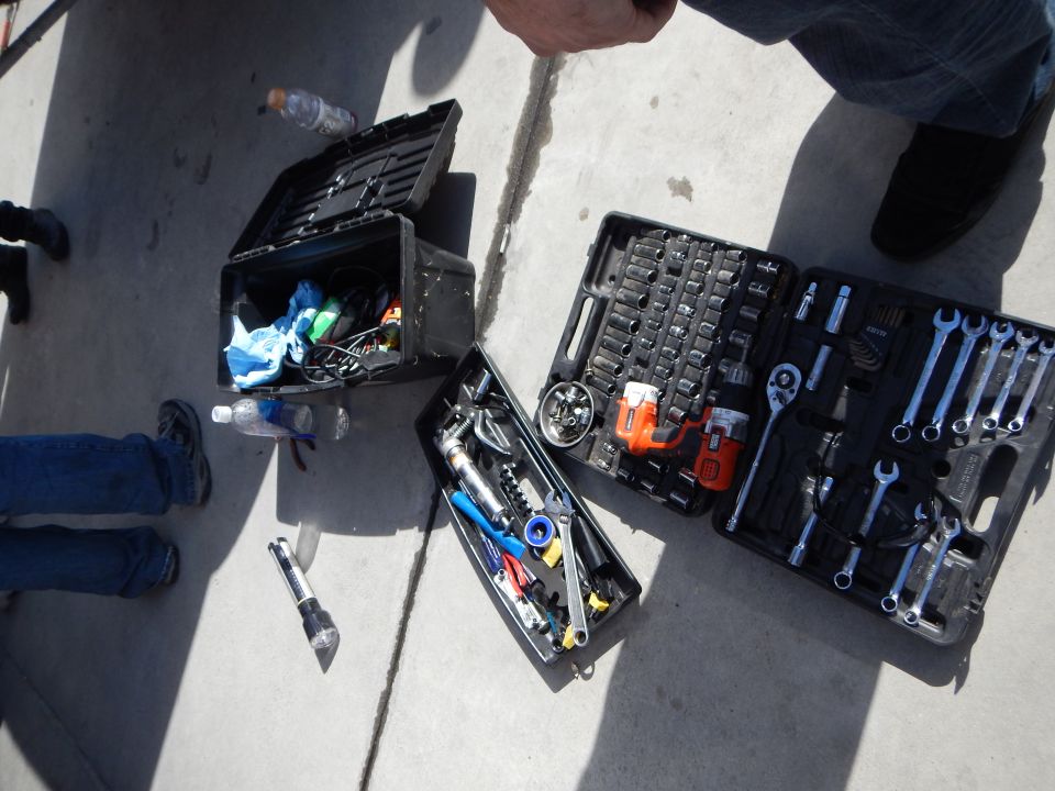 Open mechanic's tool kit and socket set laid out on a concrete floor