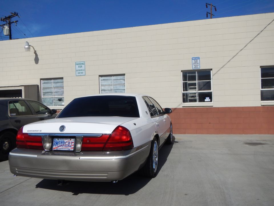 Rear of a white Mercury Grand Marquis LS sedan parked by a building