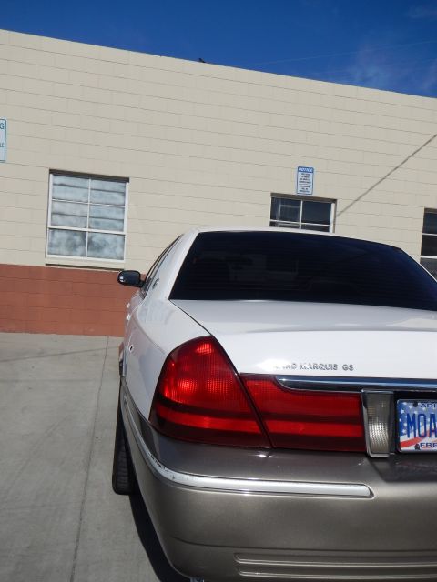 2003 Ford Crown Victoria - Close rear-quarter view of a white-over-tan Mercury Grand Marquis GS sedan showing its tinted window and taillight.