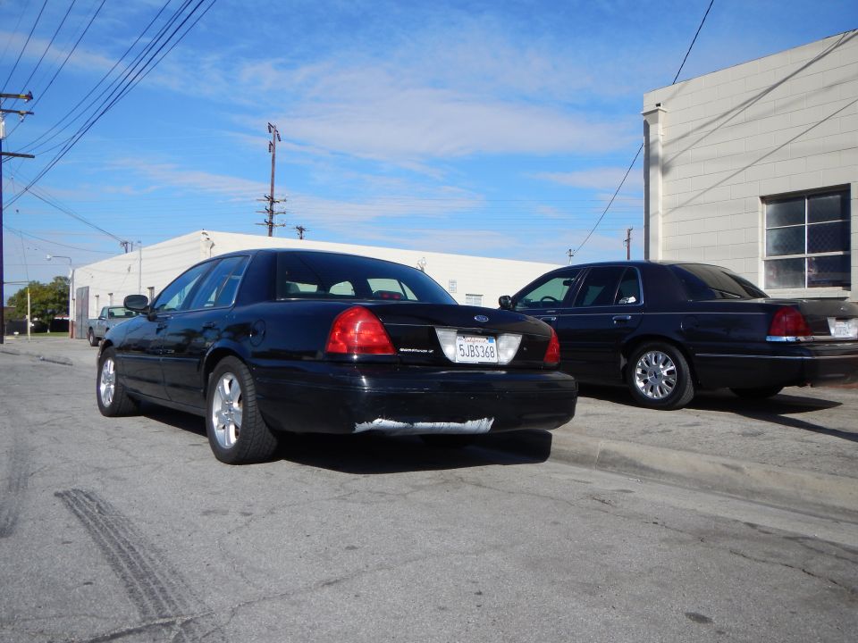 Rear view of two dark Ford sedans parked in a lot