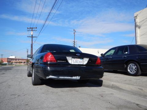 2003 Ford Crown Victoria - black Ford Crown Victoria sedan photographed from the rear shows its trunk badge, Ford emblem and California plate 5JBS368.