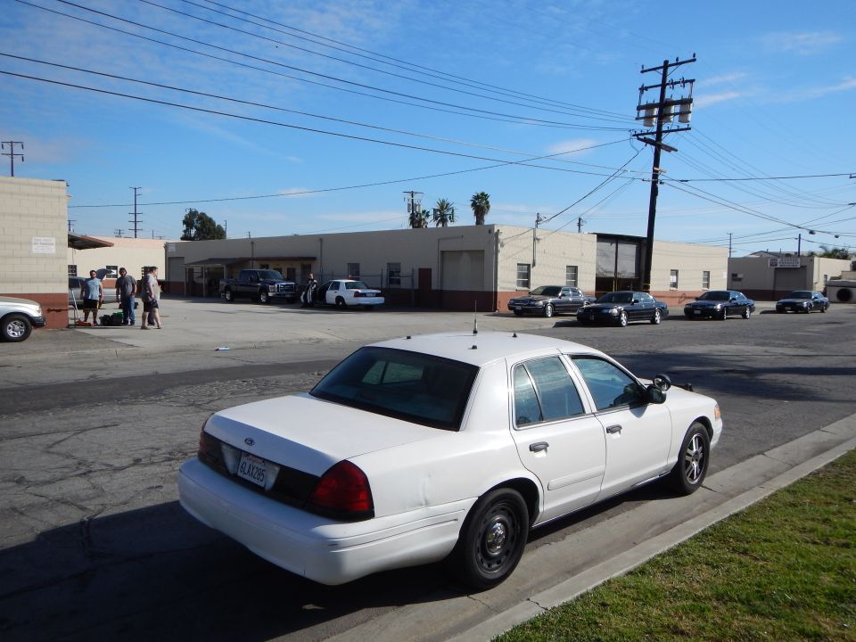 White Ford sedan rear three-quarter with California plate in lot