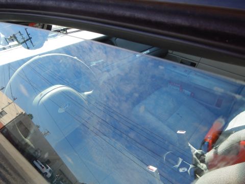 2003 Ford Crown Victoria - Reflective view through a windshield revealing a faint interior and dashboard with overhead power wires mirrored in the glass.