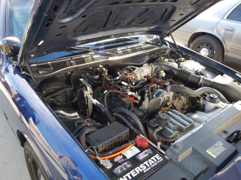 2003 Ford Crown Victoria - engine bay of a blue car is open showing a V8 engine, air intake, and an Interstate brand battery.