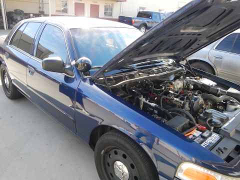 2003 Ford Crown Victoria - blue Ford Crown Victoria sits with its hood up revealing the engine bay, parked in a lot near other vehicles.