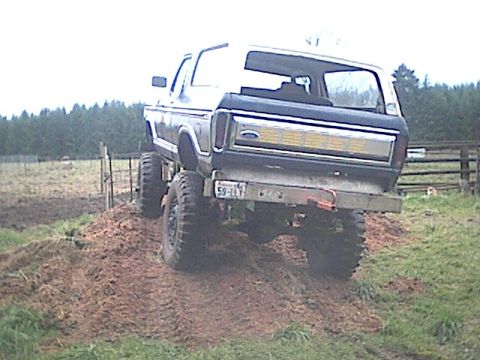 1978 Ford Bronco - This lifted 1978 Ford Bronco navigates a muddy incline, its off-road capabilities.