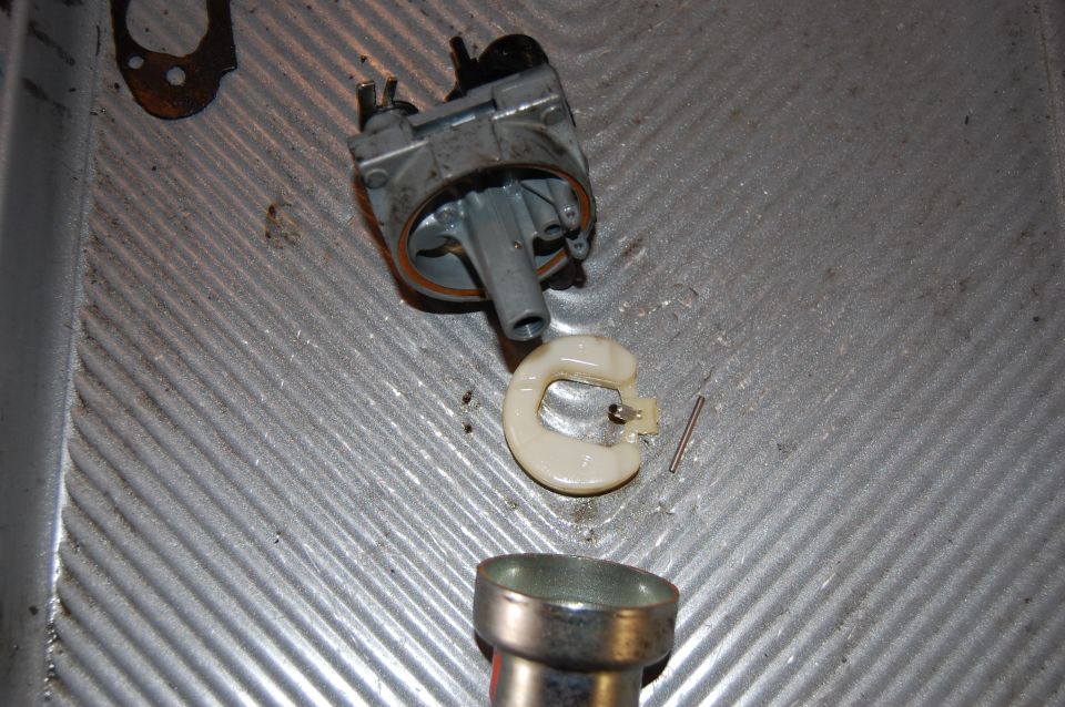 Carburetor body, float, and gasket on a metal surface