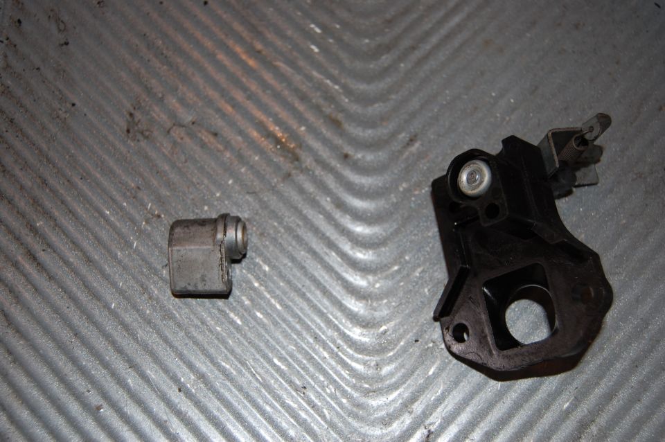 Two carburetor parts on a textured surface