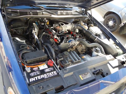 2003 Ford Crown Victoria - engine bay of a blue vehicle is open showing the V8 engine, hoses, and an Interstate battery at the front.