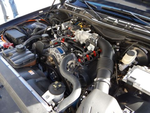 2003 Ford Crown Victoria - close-up of an engine bay shows the alternator, black air intake tube, fluid reservoirs, and wiring.
