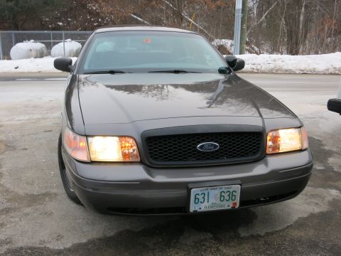 2001 Ford Crown Victoria - The front of a 2001 Ford Crown Victoria is shown with the headlights illuminated.