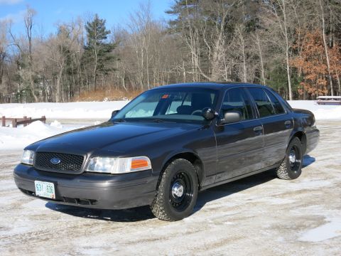 2001 Ford Crown Victoria - Dark gray 2001 Ford Crown Victoria sits on a snowy lot with trees in the background.