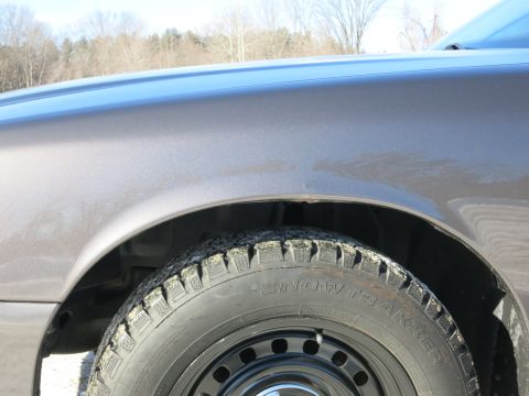 2001 Ford Crown Victoria - A close-up view of a car's fender and a snow tire, with text visible on the tire's sidewall.