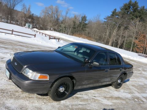 2001 Ford Crown Victoria - A Ford Crown Victoria sits parked on a snow-covered surface under a clear blue sky.