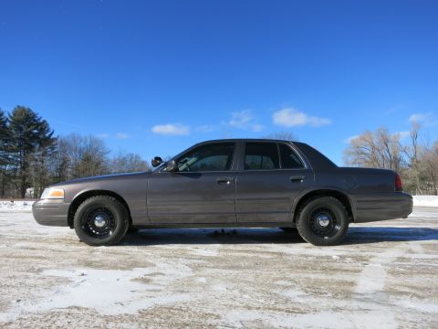 2001 Ford Crown Victoria - Side view of a 2001 Ford Crown Victoria parked on a snowy surface under a clear blue sky.