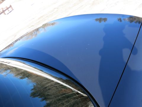 2001 Ford Crown Victoria - The top of a dark blue car shows reflections of the surrounding winter landscape.