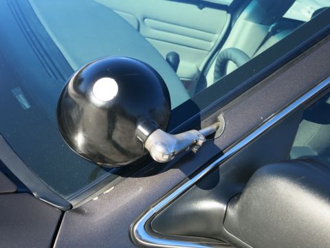 2001 Ford Crown Victoria - A spotlight is attached to the exterior of a vehicle, with parts of the interior visible through the windshield.
