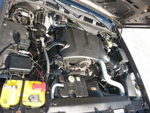 2001 Ford Crown Victoria - The engine bay of a 2001 Ford Crown Victoria is visible, a yellow battery and black engine cover.