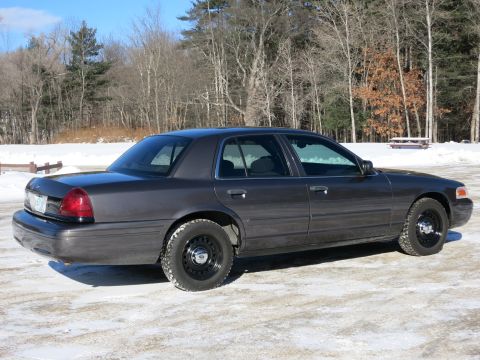 2001 Ford Crown Victoria - A dark gray 2001 Ford Crown Victoria is parked in a snowy area with trees in the background.