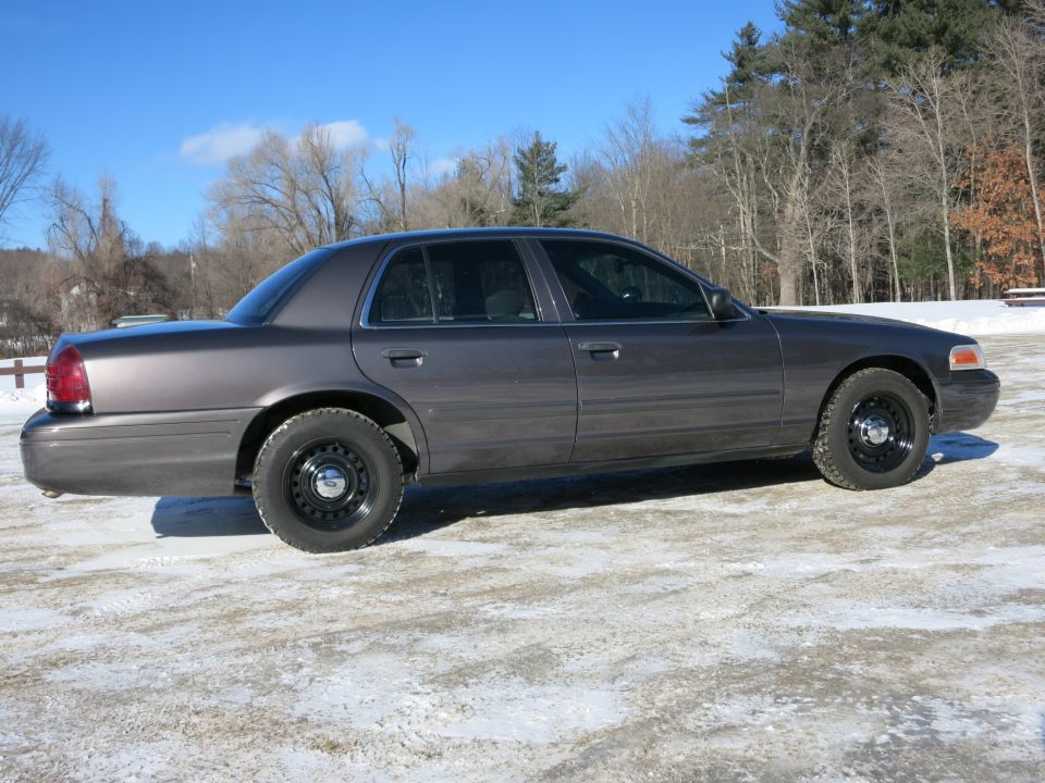 Dark gray 2001 Ford Crown Victoria sedan parked on a snowy surface, viewed from the side
