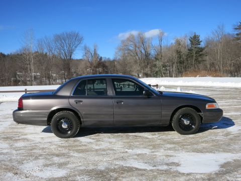 2001 Ford Crown Victoria - Side profile of a gray 2001 Ford Crown Victoria sedan captured on a bright, cold day with snow on the ground.