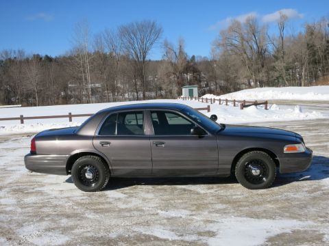 2001 Ford Crown Victoria - A gray 2001 Ford Crown Victoria is parked outside in a snowy area with trees in the background.