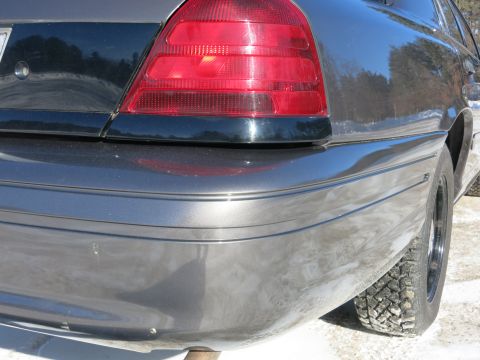 2001 Ford Crown Victoria - The rear of a 2001 Ford Crown Victoria is visible, with a scratch on the bumper and a close-up of the taillight.