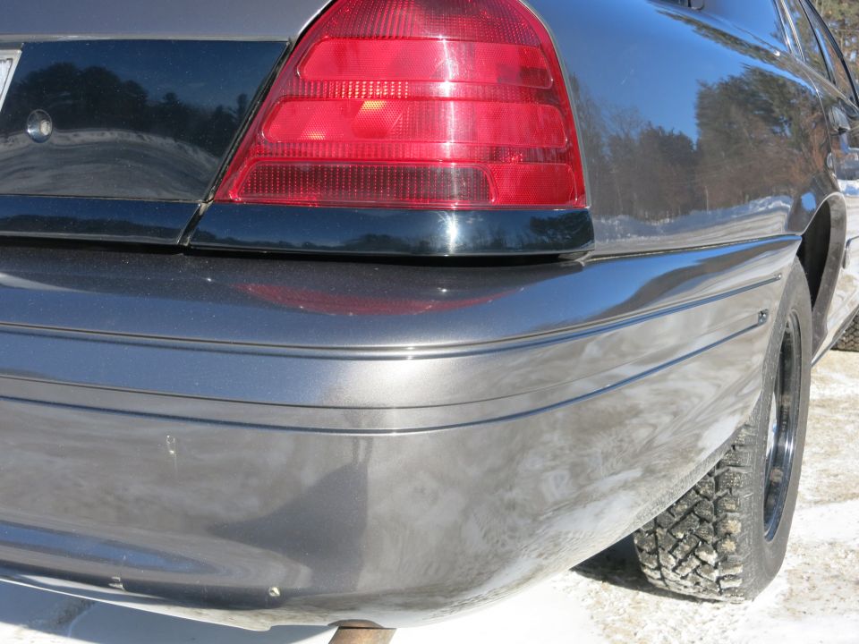 Dark gray 2001 Ford Crown Victoria rear quarter panel and taillight, showing a scratch on the bumper