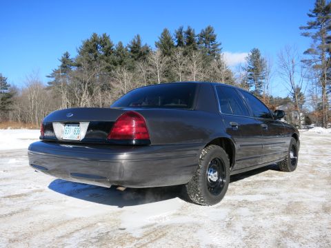 2001 Ford Crown Victoria - Rear 3/4 view of a dark gray 2001 Ford Crown Victoria parked in a snowy area with trees in the background.