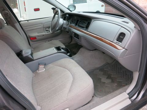 2001 Ford Crown Victoria - The interior of a car is shown, fabric seats and a dashboard with wood grain trim.