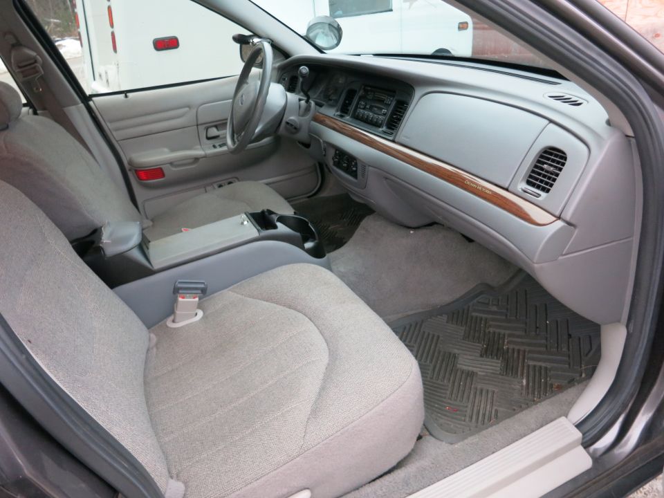 Interior of a car showing front seats, dashboard, and center console. Wood trim accents the dashboard